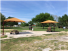 Two canopies over picnic tables near a grill