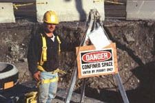 Worker Standing Next to Sign which Reads "Danger, Confined Space"