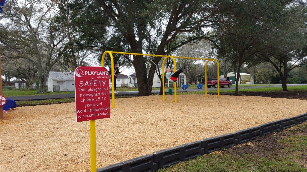 Highland Park Playground safety sign with kid swinging in the background