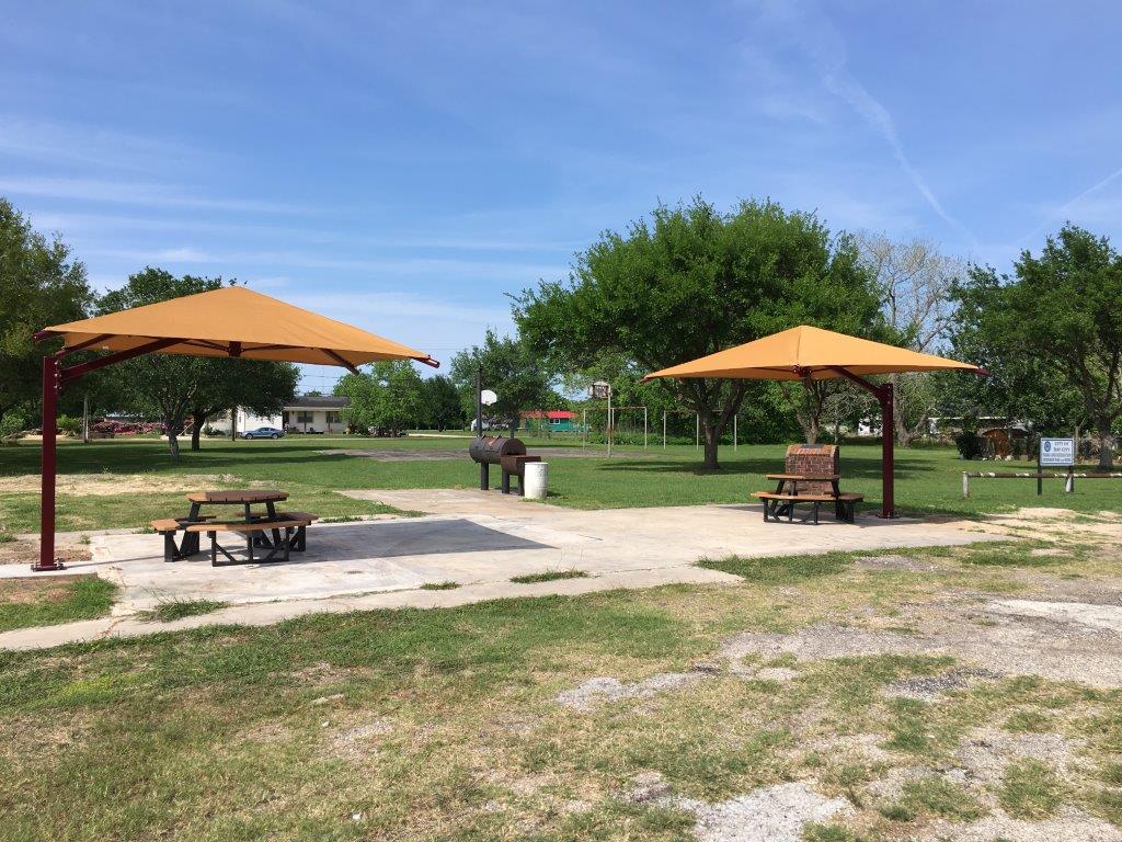 Two canopies over picnic tables near a grill